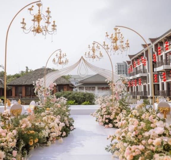 White aisle beneath gold chandelier arches lined with blush flowers
