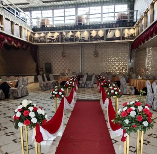 Red carpet aisle lined with gold stands, red and white roses and swagged fabric