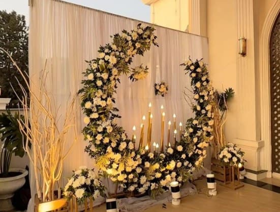 Crescent arch of white flowers and candles against an ivory drape