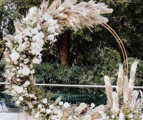 Gold ring arch with white orchids and pampas grass in a garden
