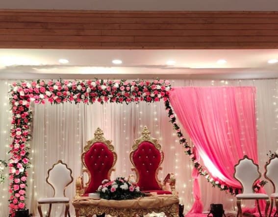 Pink rose frame with a pink drape, red throne chairs and a carved centre table