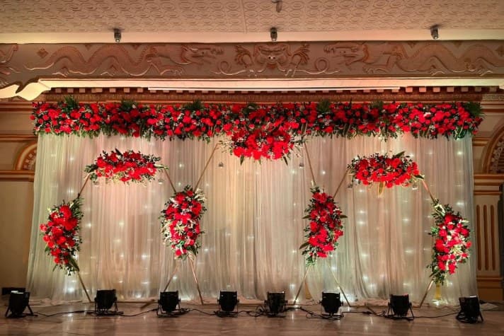 Wide stage with a fairy-light curtain, red rose garland and gold hexagon frames dressed in red roses